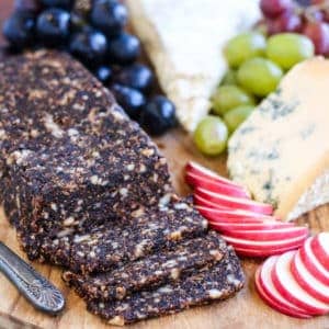 A Pan de Higo cutting board with cheese, grapes and nuts.