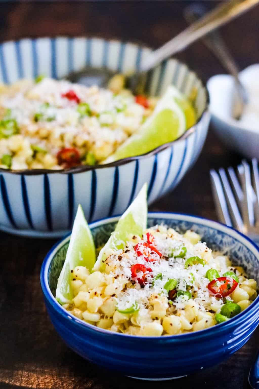 Mexican corn salad served with lime wedges.