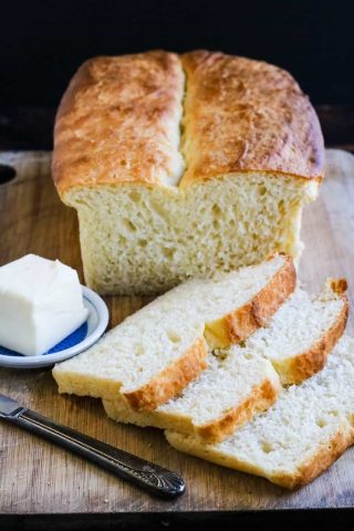 Sliced homemade bread on a cutting board with butter