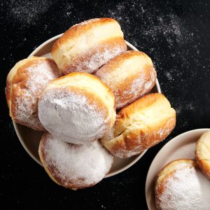 Powdered doughnuts (sufganiyot) on a plate with powdered sugar.