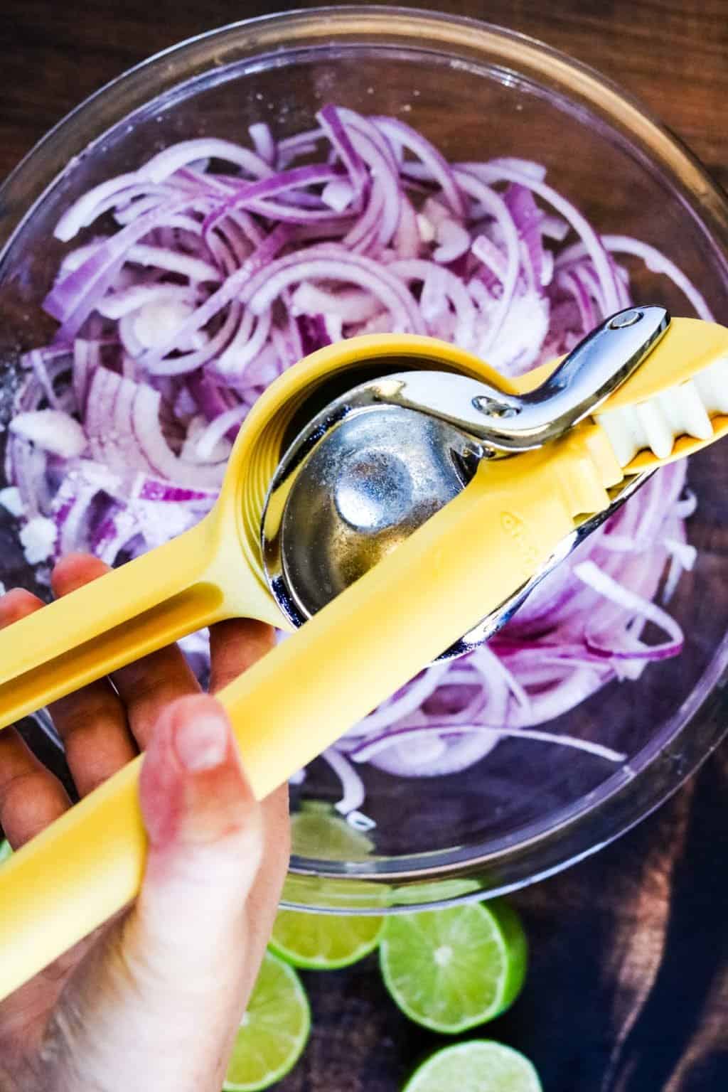 Squeezing lime juice over red onions to make Mexican pickled onions