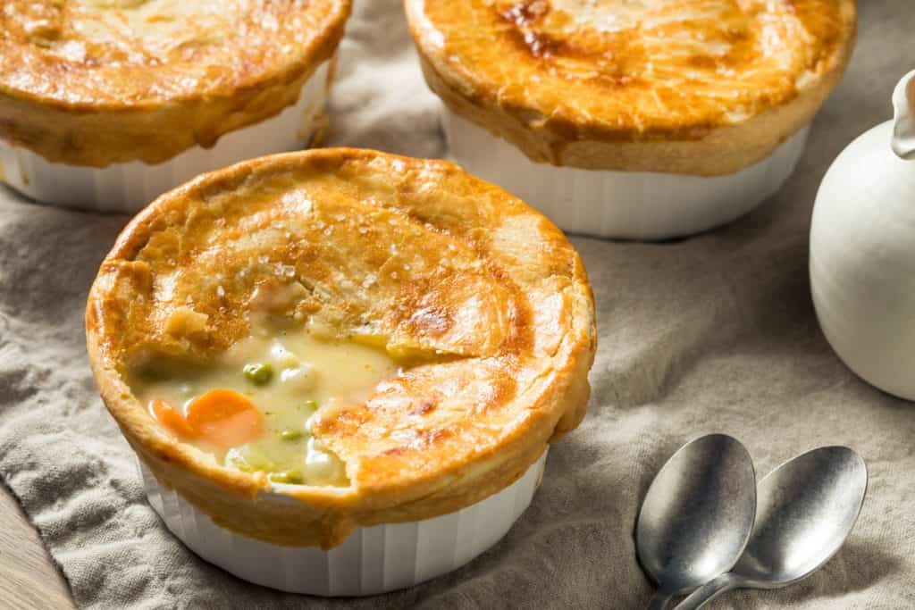 three mini chicken pot pies in white ramekins, shot from a low angle.