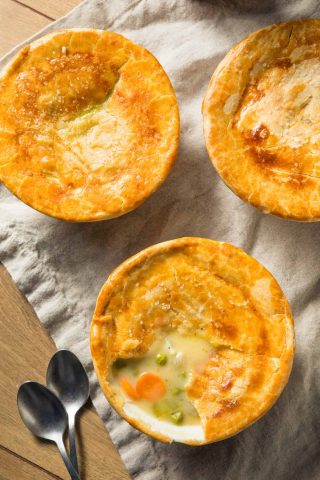 Three chicken pot pies on a wooden table.