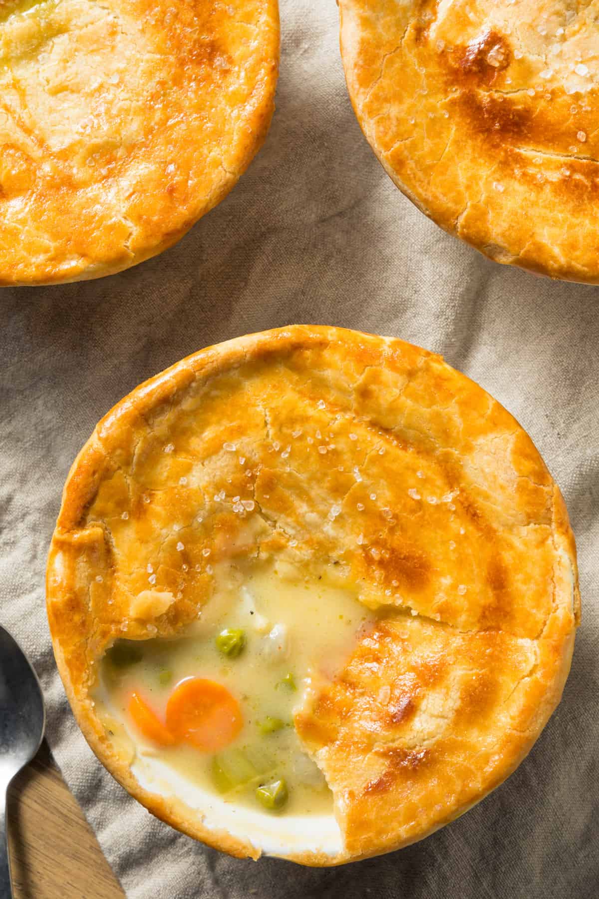 three mini chicken pot pies in white ramekins, shot from overhead.
