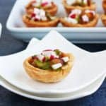 single salt cod tartlet on plate iwth tray of them behind