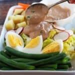 spooning thai peanut sauce onto gado gado salad