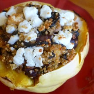 A stuffed acorn squash on a red plate.