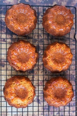 A group of honey bundt cakes on a cooling rack.