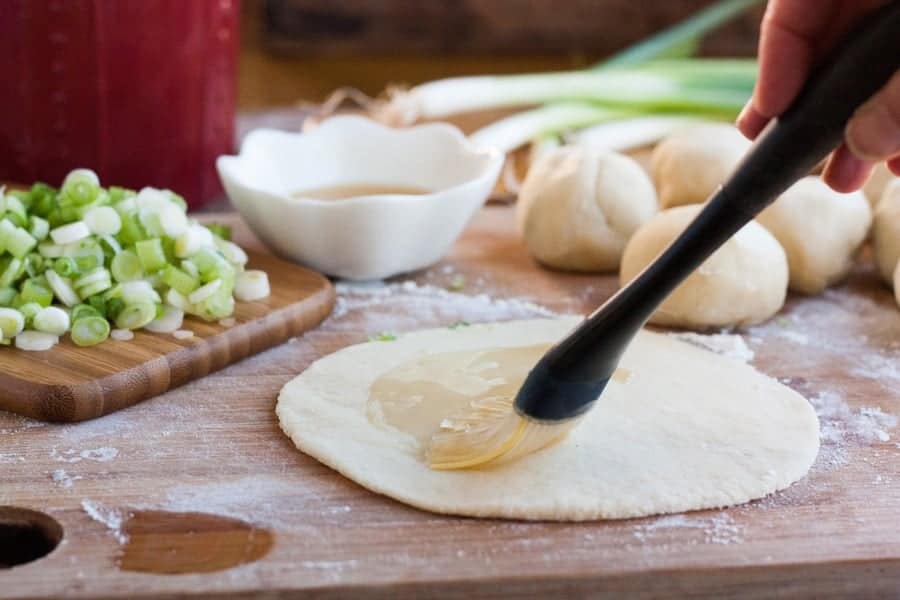 Brushing oil on the dough rounds for crispy scallion pancakes