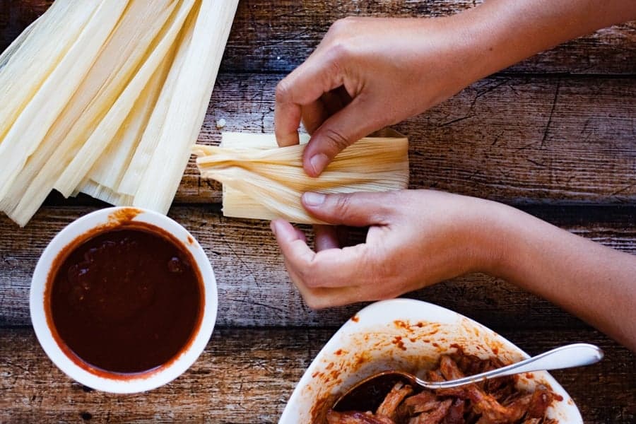folding corn husk around filled homemade tamales