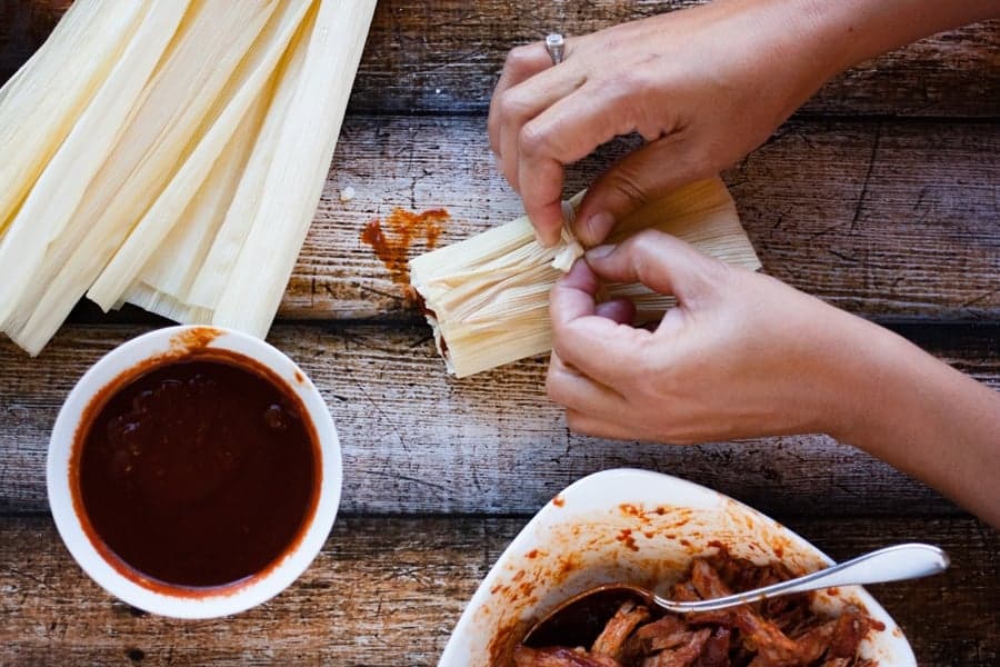 tying the corn husk around a filled tamale