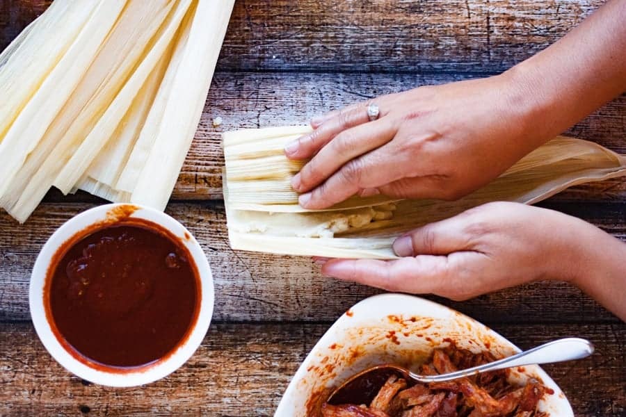  wrapping filled tamales in corn husks