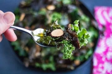 kale salad on a fork with a sliver of almond.