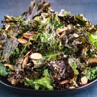 Kale salad with almonds and miso dressing in a bowl.
