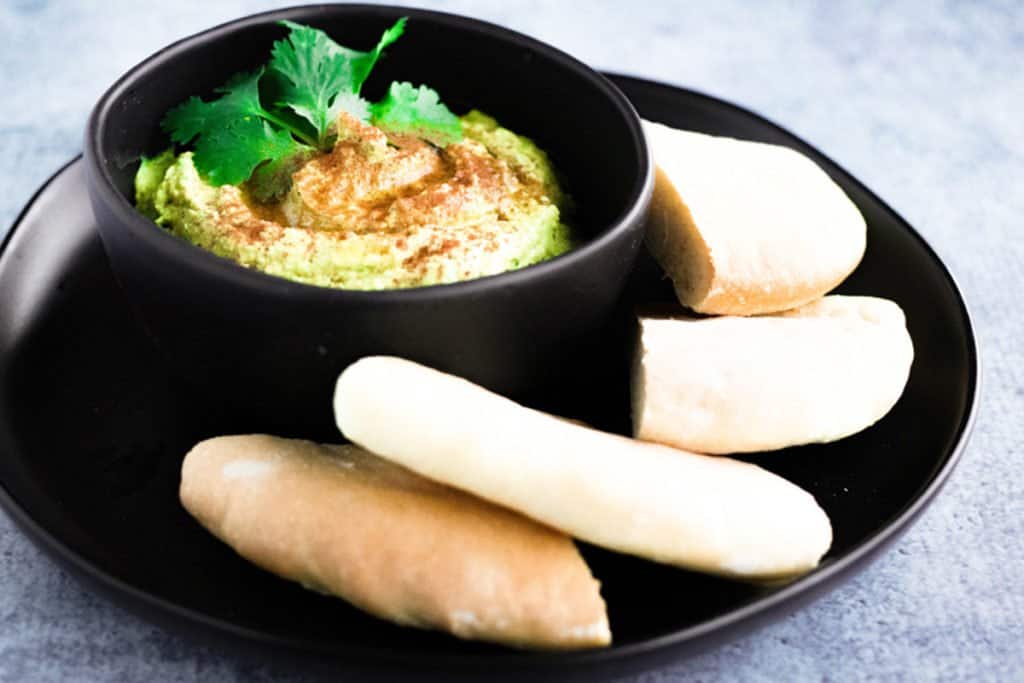 Curry hummus with cilantro on the top and pita on the side.