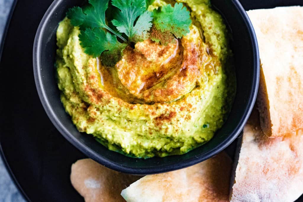Curry hummus with cilantro on the top and pita on the side.