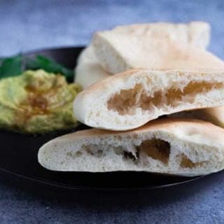 A plate of homemade pita bread with hummus and guacamole.