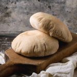 A homemade pita bread on a wooden cutting board.