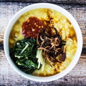 Crispy fried shallots on top of a bowl of turmeric congee.