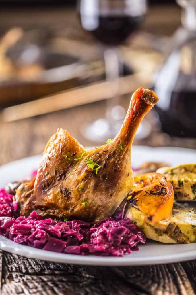 Roasted duck with red cabbage and wine served on a white plate - Duck Confit Recipe.