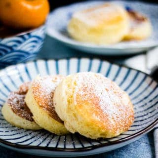 three japanese pancakes, dusted with powdered sugar, on a japanese plate. they look delicious
