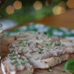 A jar of chicken liver pâté on a wooden board with a glass of wine.