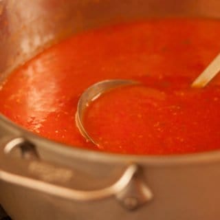 Low angle shot of roasted tomato soup in a stockpot with a ladle.