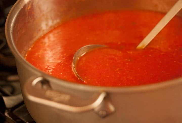 Low angle shot of roasted tomato soup in a stockpot with a ladle.