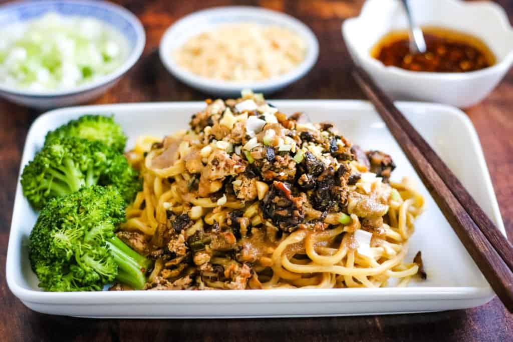 A vegetarian plate with dan dan noodles and broccoli on it.