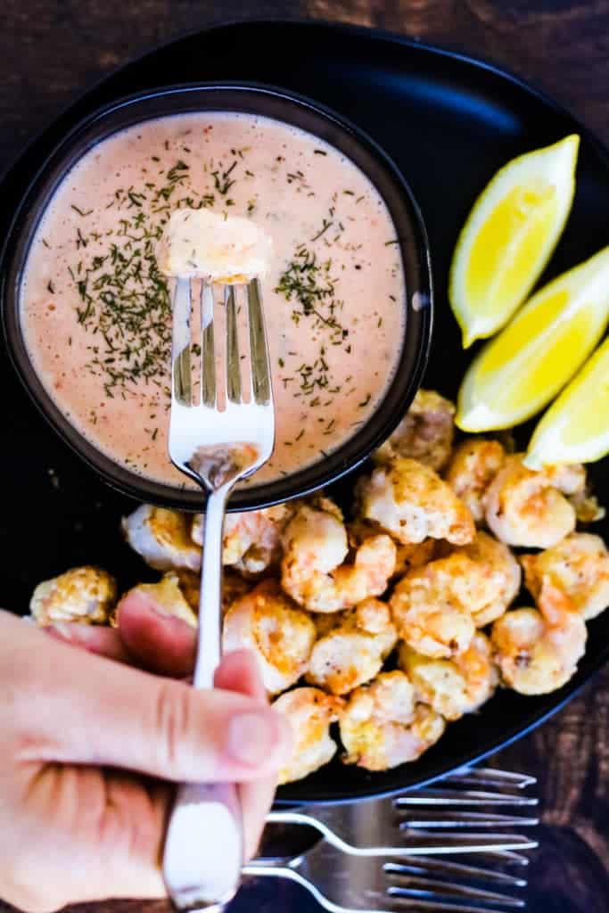 air fryer bang bang shrimp on a plate shot from overhead with a shrimp that has been dipped in the sauce on a fork