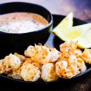 A plate of air fryer bang bang shrimp served with dipping sauce.