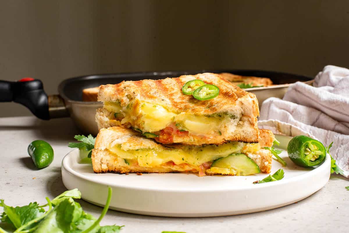 A Bombay sandwich with jalapeno and cheese on a plate.