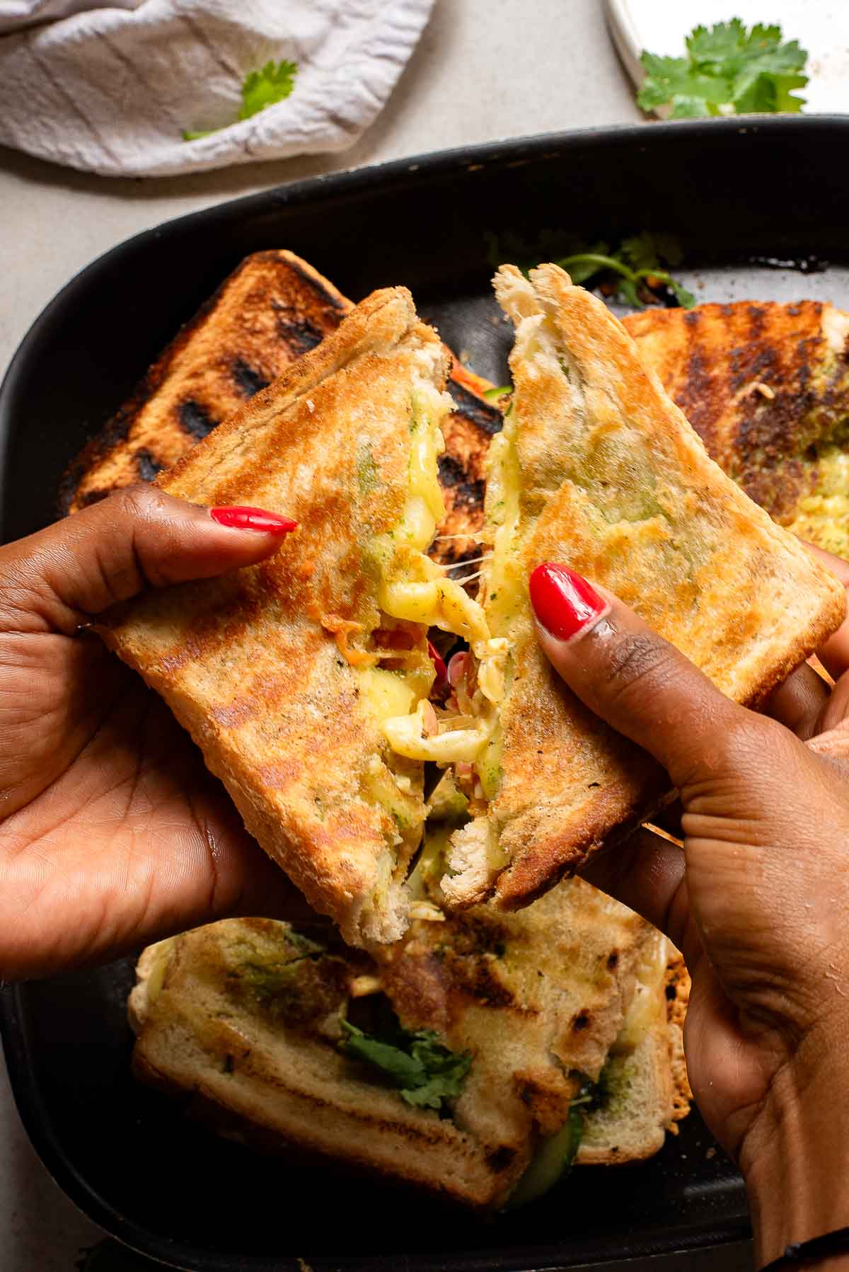 Hands pulling apart a Bombay Sandwich.