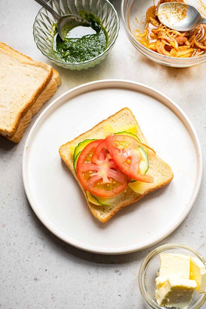 a slice of bread with potato, cucumber and tomato slices on top.