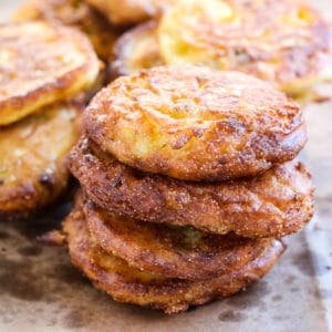 A stack of fried green tomato pancakes on a baking sheet.