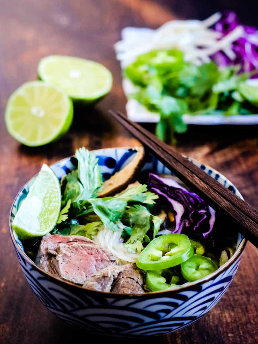 low angle photo of a bowl of beef pho with garnishes
