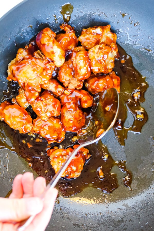 tossing chicken with sauce in a pan