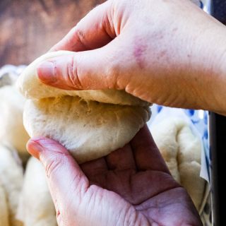 Chinese steamed bun being pulled open by hands