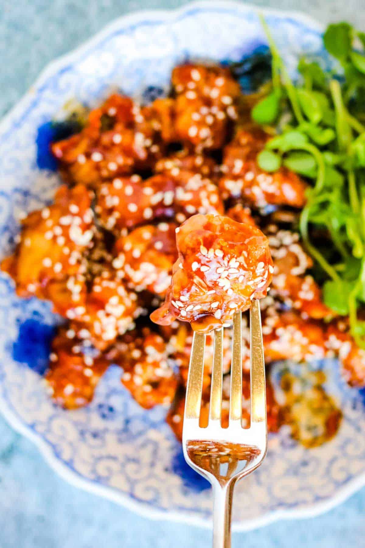 A fork with sesame chicken on it.