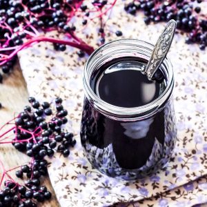 Step-by-step guide on how to make elderberry syrup using berries and spoon.