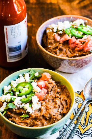 Two bowls of black bean soup with refried beans and sour cream.