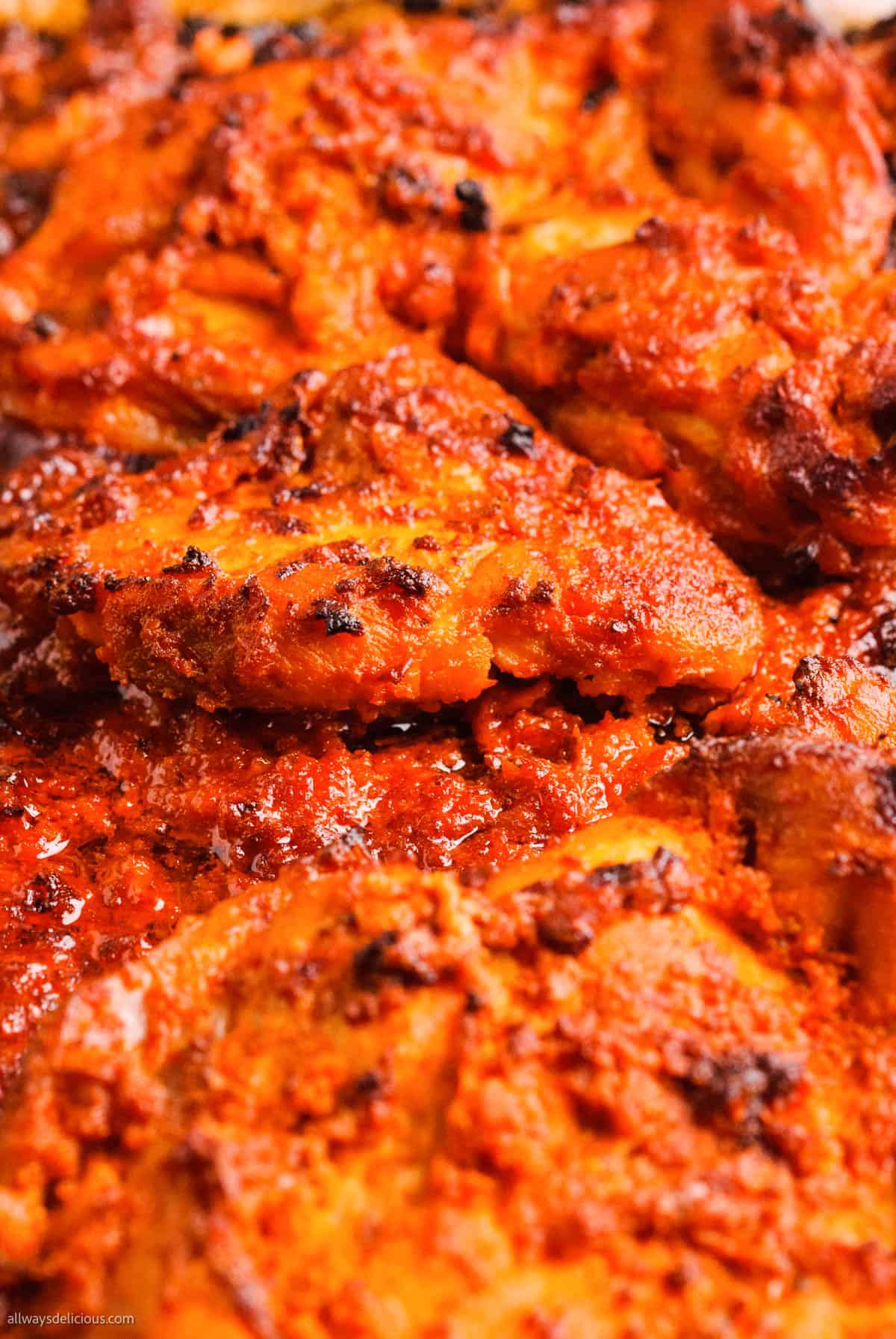 A close up of a harissa chicken dish in a red sauce.