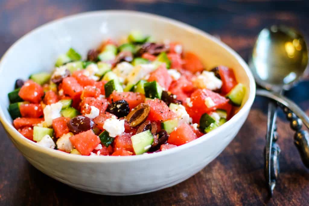 Watermelon and feta salad with cucumbers and kalamata olives in a white bowl