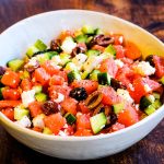 low angle shot of watermelon and feta salad in a white salad bowl.