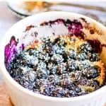 A baked blueberry clafoutis in a white ramekin, dusted with powdered sugar. Text reads "Blueberry Clafoutis" at the top and "allwaysdelicious.com" at the bottom.