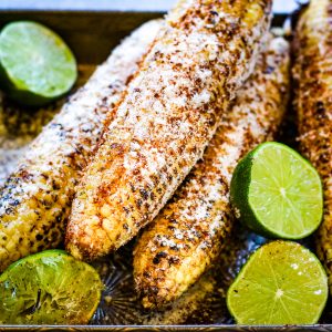 Low angle shot of grilled Mexican corn with limes, sprinkled with chili powder and grated cheeese