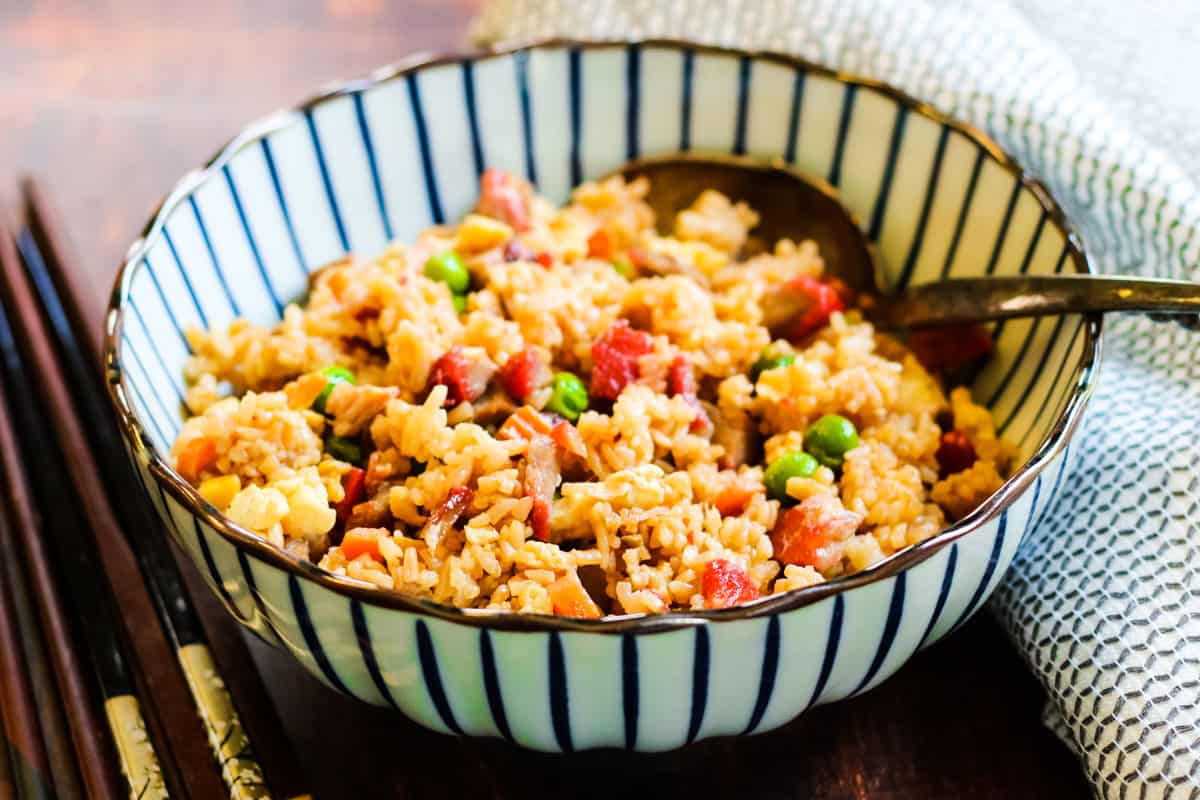 A delicious pork fried rice recipe served in a bowl with a serving spoon.