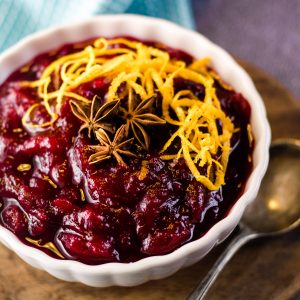 low angle shot of a bowl of cranberry sauce with grated orange zest and star anise pods on top