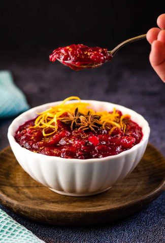 cranberry sauce in a white bowl wit a spoonful being lifte up