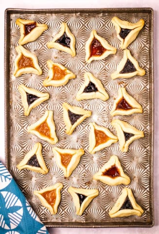Hamantaschen baked with jam on a sheet.